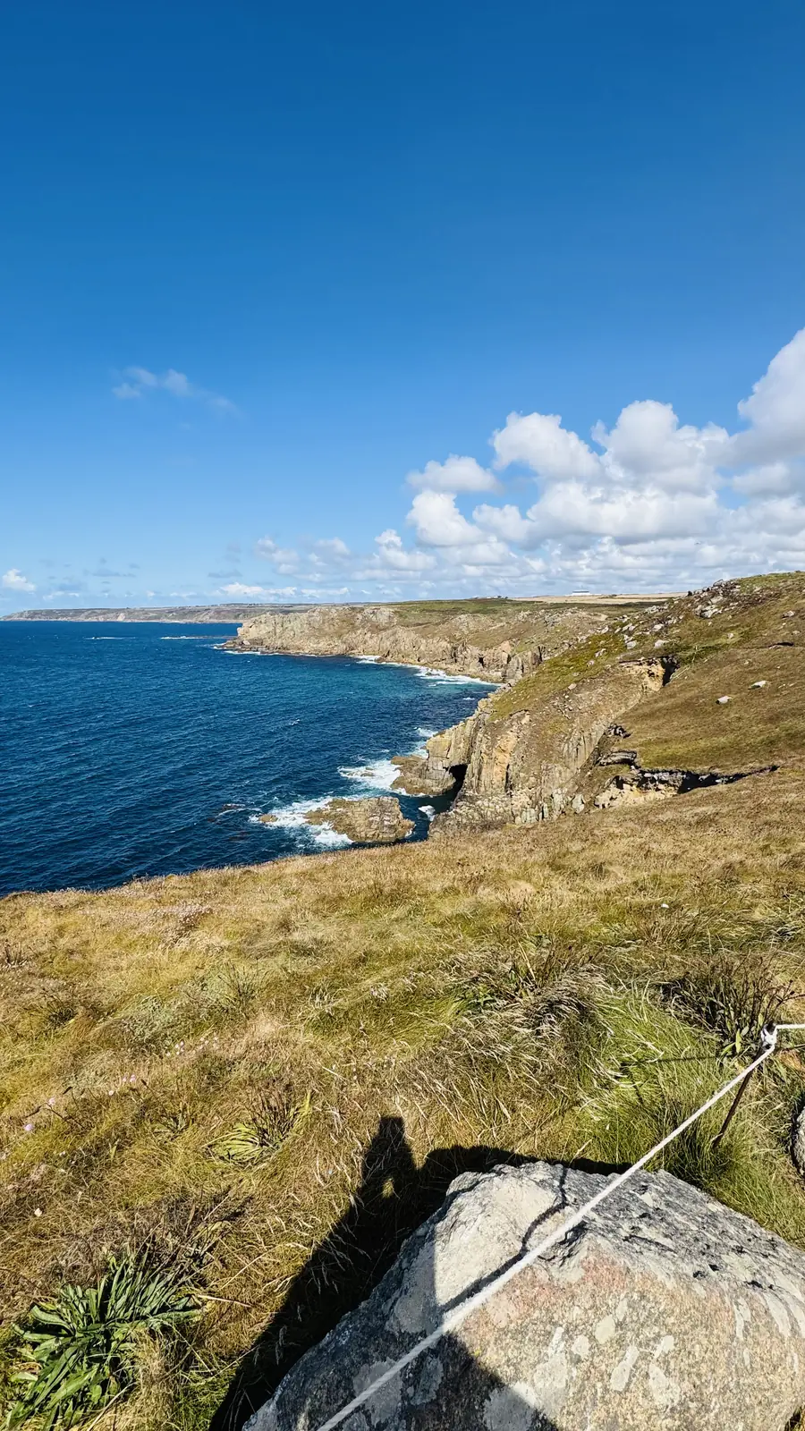 A narrow coastal footpath crossing grass above rocky coves near Land's End
