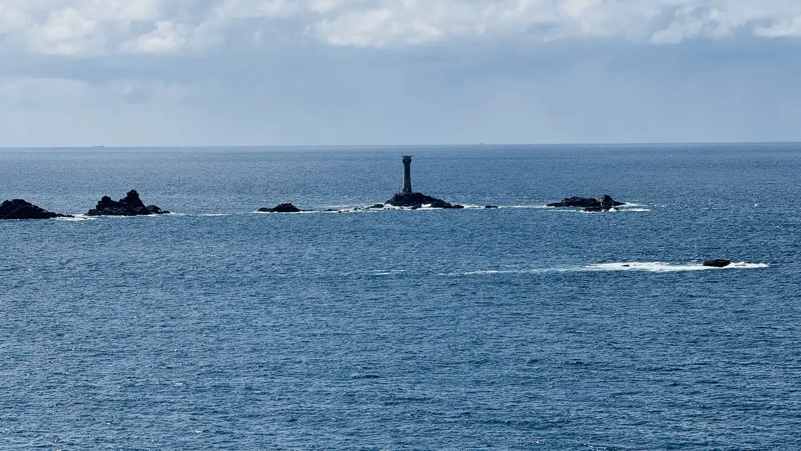 Longships Lighthouse standing among low dark rocks in the Atlantic off Land's End